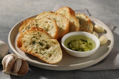 Photo of Tasty baguette with garlic and dill served on grey textured table