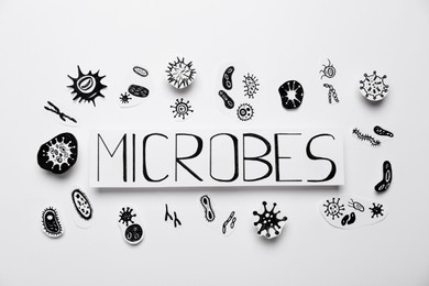 Photo of Card with word Microbes and pictures on white background, flat lay