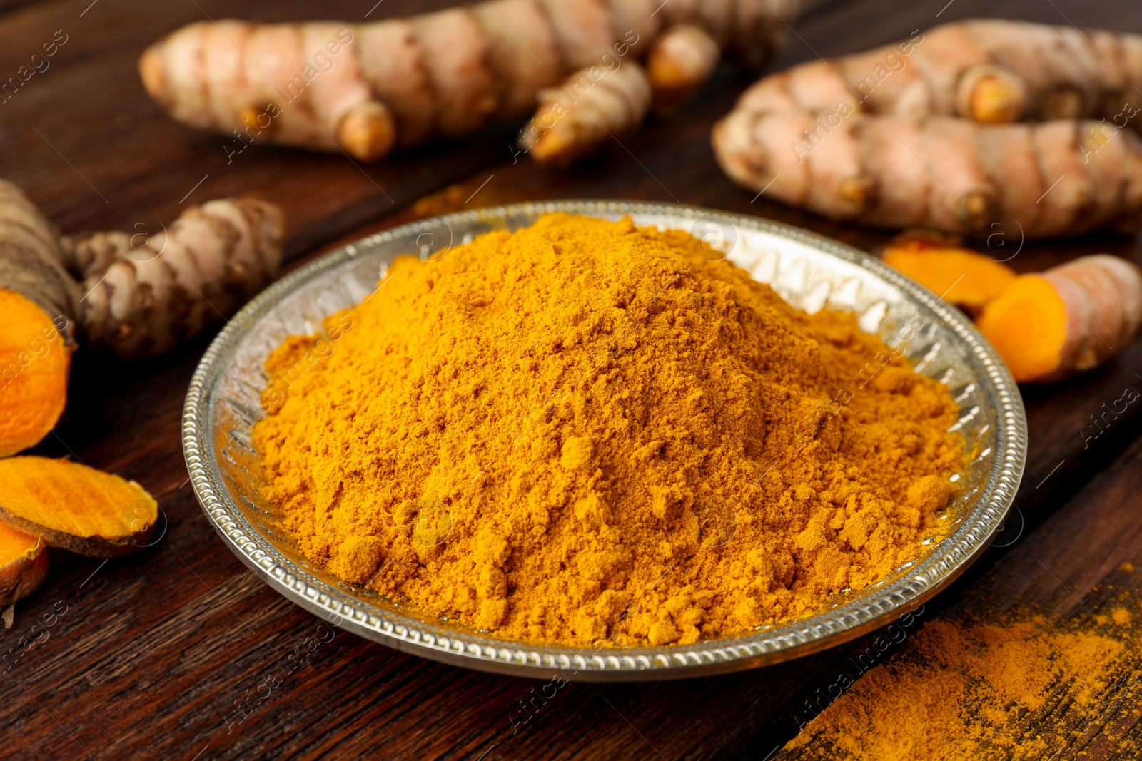 Photo of Plate with aromatic turmeric powder on wooden table, closeup