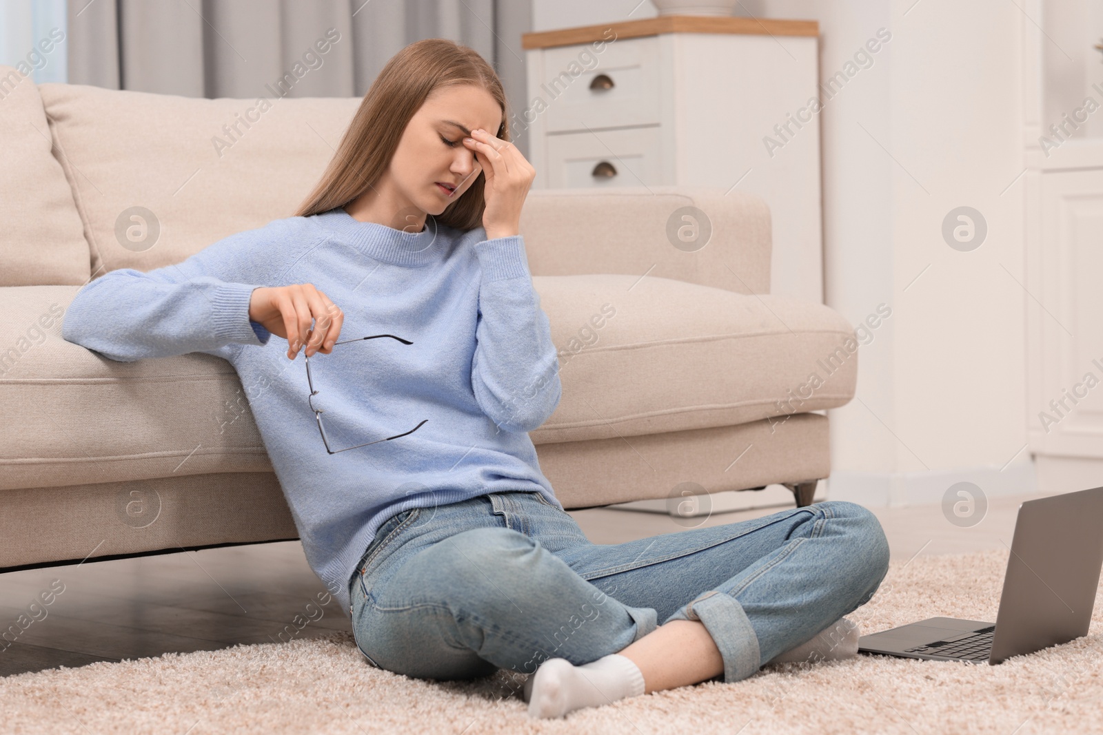 Photo of Overwhelmed young woman sitting with laptop on floor at home