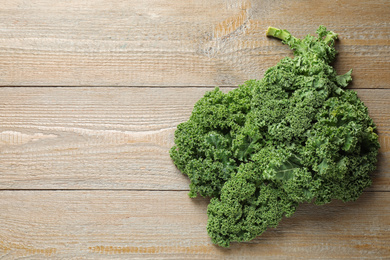 Photo of Fresh kale leaves on wooden table, top view. Space for text