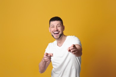 Photo of Handsome man laughing on yellow background. Funny joke