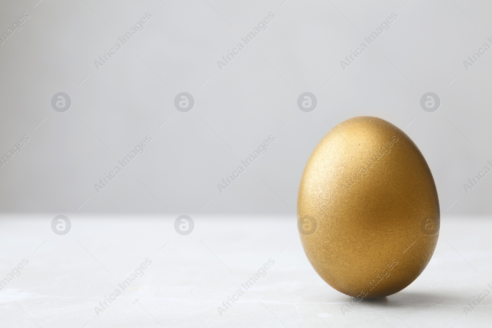 Photo of One shiny golden egg on table, space for text