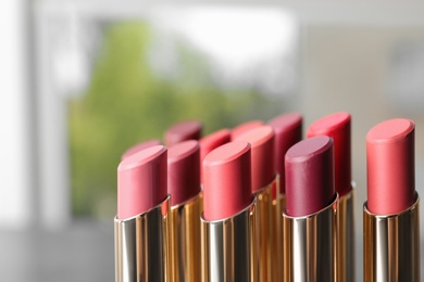 Photo of Set of bright lipsticks on blurred background. Space for text
