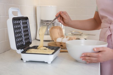 Photo of Woman pouring dough onto Belgian waffle maker in kitchen, closeup