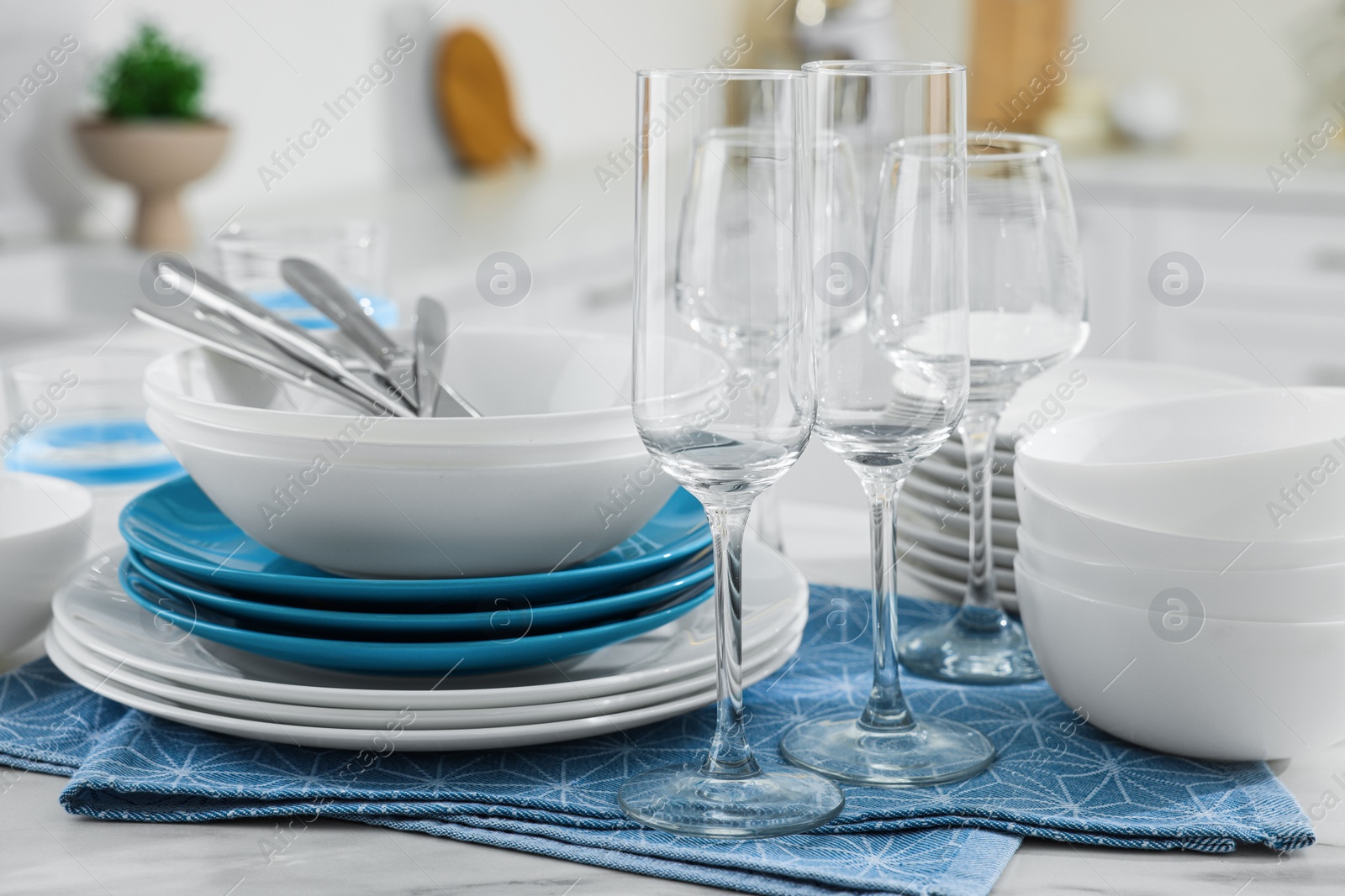 Photo of Different clean dishware, cutlery and glasses on white table in kitchen, closeup