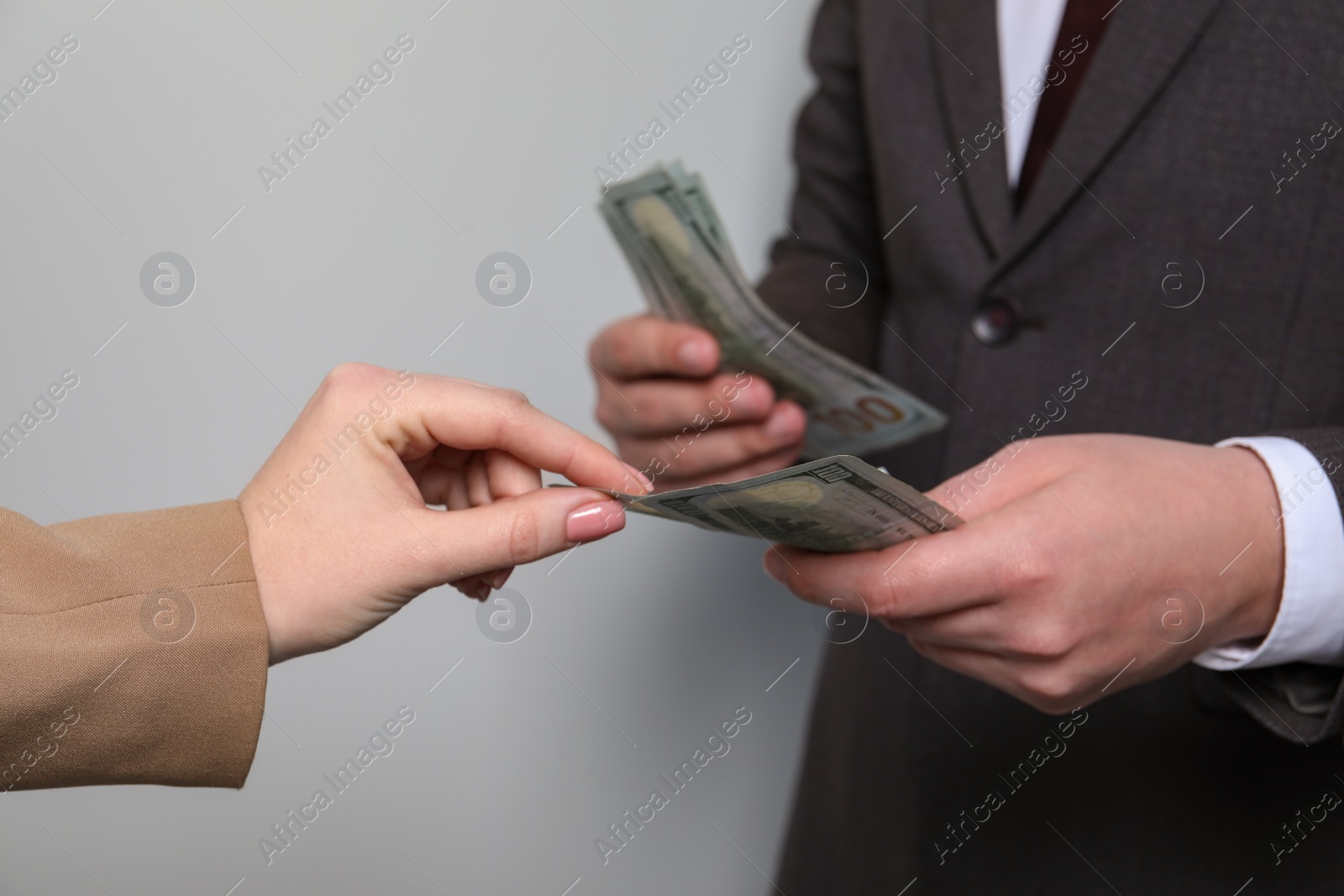 Photo of Man giving money to woman on light grey background, closeup. Currency exchange