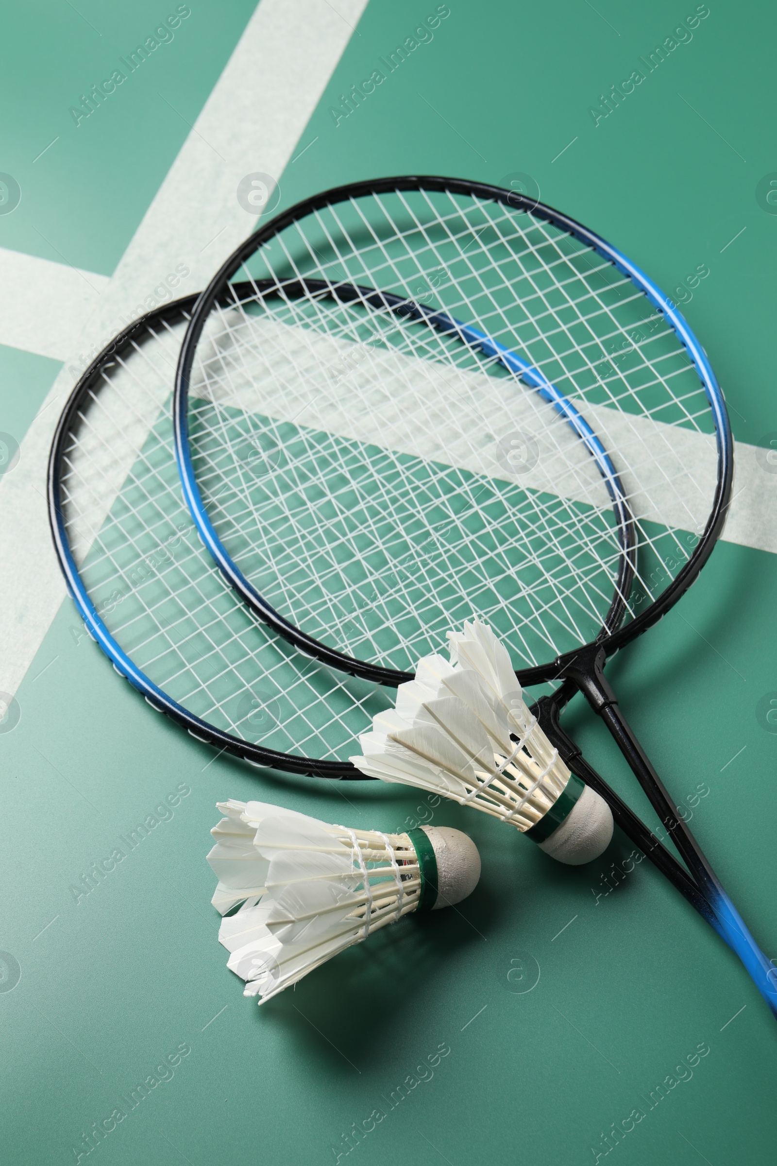 Photo of Feather badminton shuttlecocks and rackets on green table