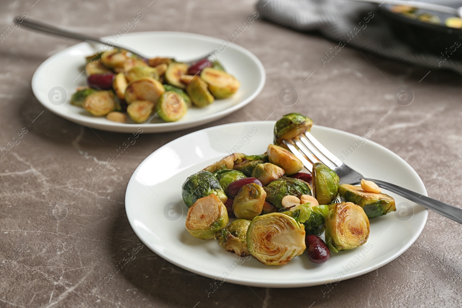 Photo of Delicious roasted brussels sprouts with red beans and peanuts served on grey marble table