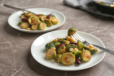 Photo of Delicious roasted brussels sprouts with red beans and peanuts served on grey marble table