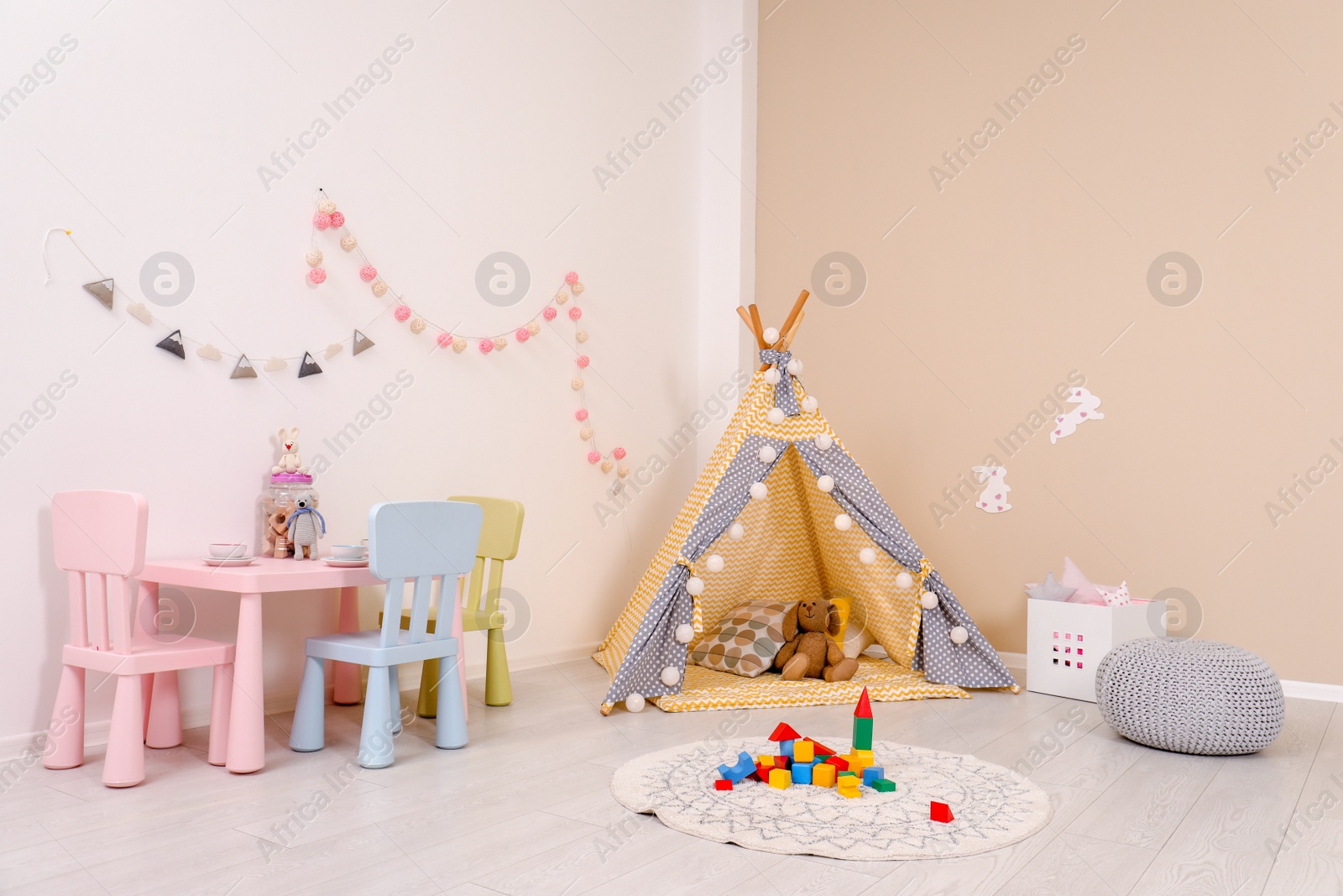 Photo of Cozy child room interior with play tent, table and modern decor elements