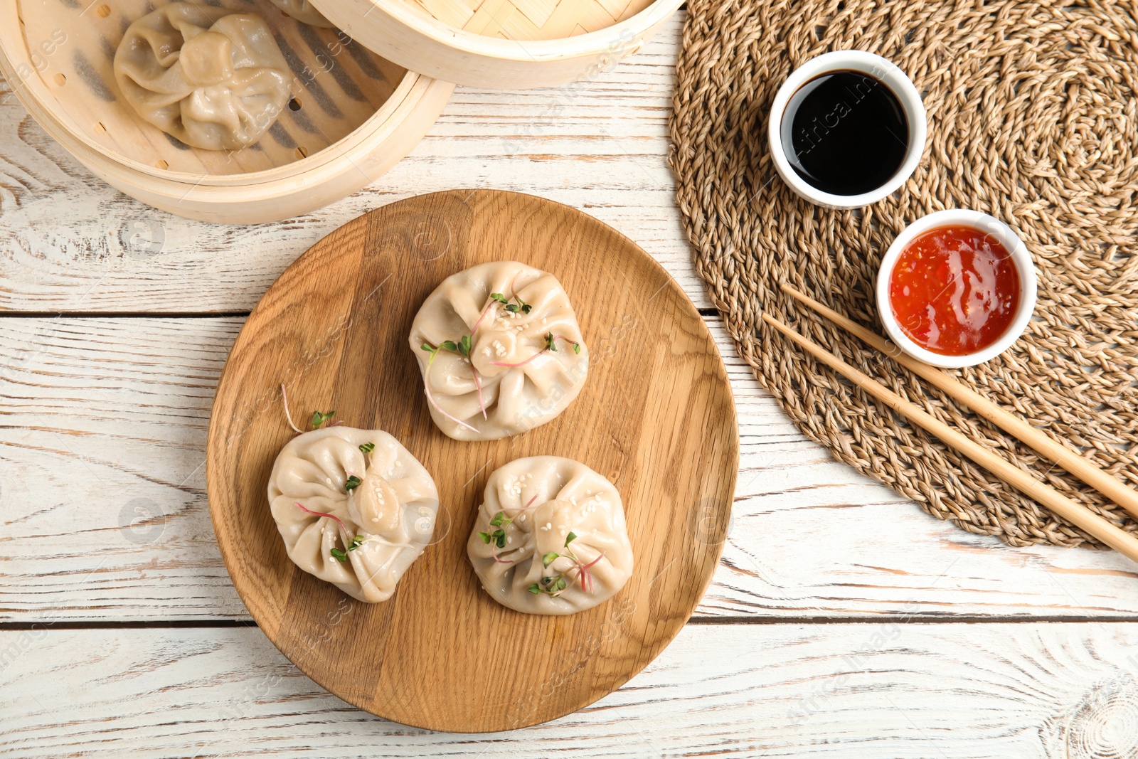 Photo of Flat lay composition with tasty baozi dumplings, bamboo steamer and sauces on white wooden table