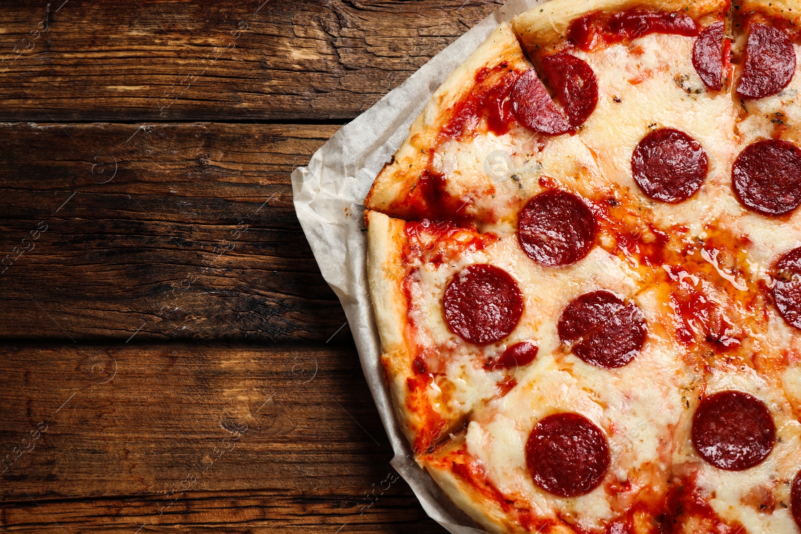 Photo of Hot delicious pepperoni pizza on wooden table, top view. Space for text