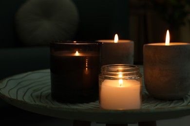 Photo of Lit candles on table in dark living room, closeup