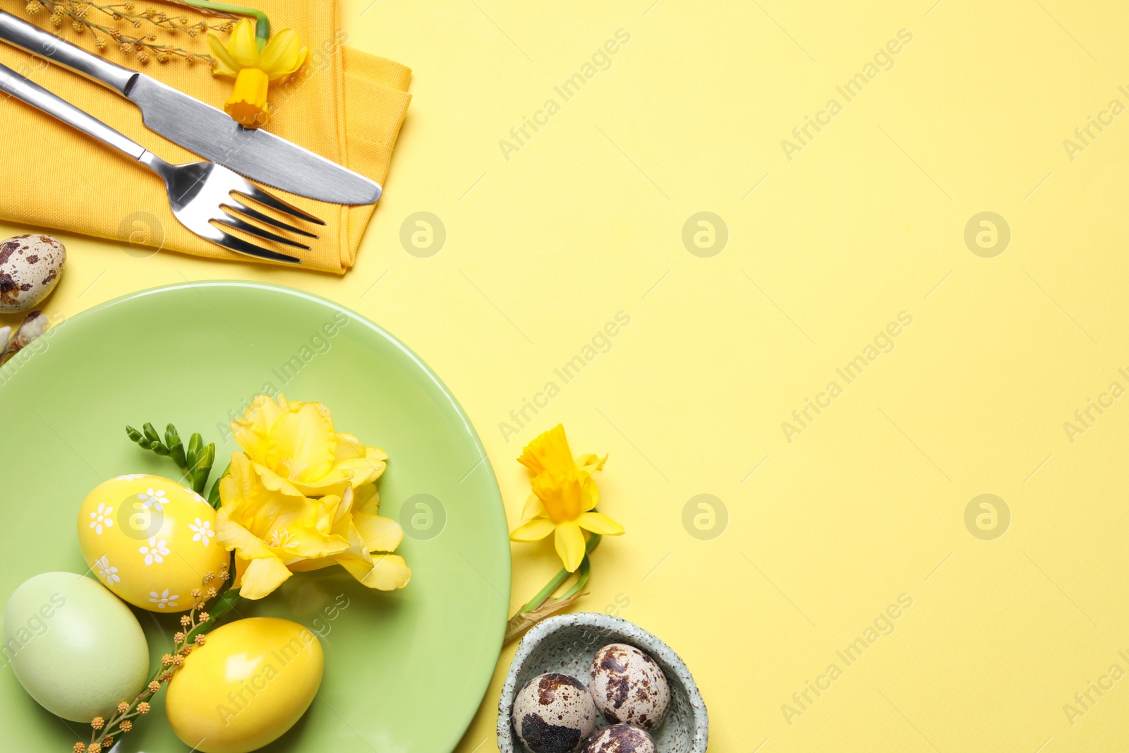 Photo of Festive Easter table setting with eggs on yellow background, flat lay. Space for text