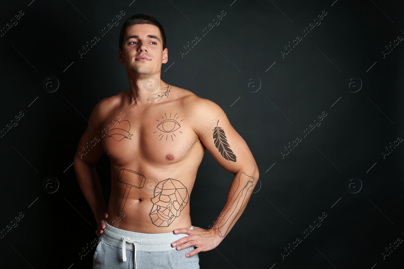 Image of Handsome man with beautiful tattoo sketches on black background. Space for text