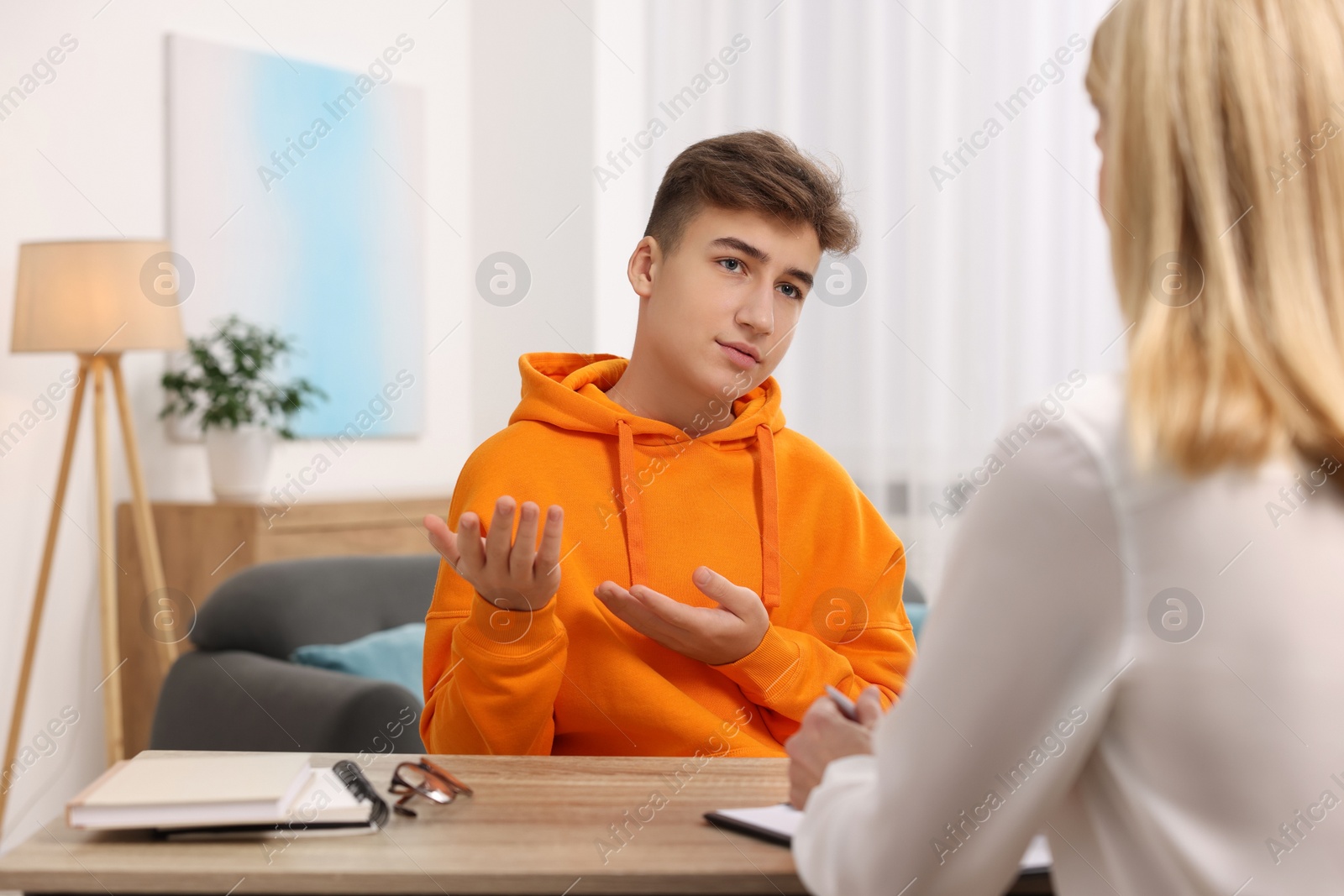 Photo of Psychologist working with teenage boy at table in office