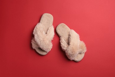 Photo of Pair of soft fluffy slippers on red background, top view