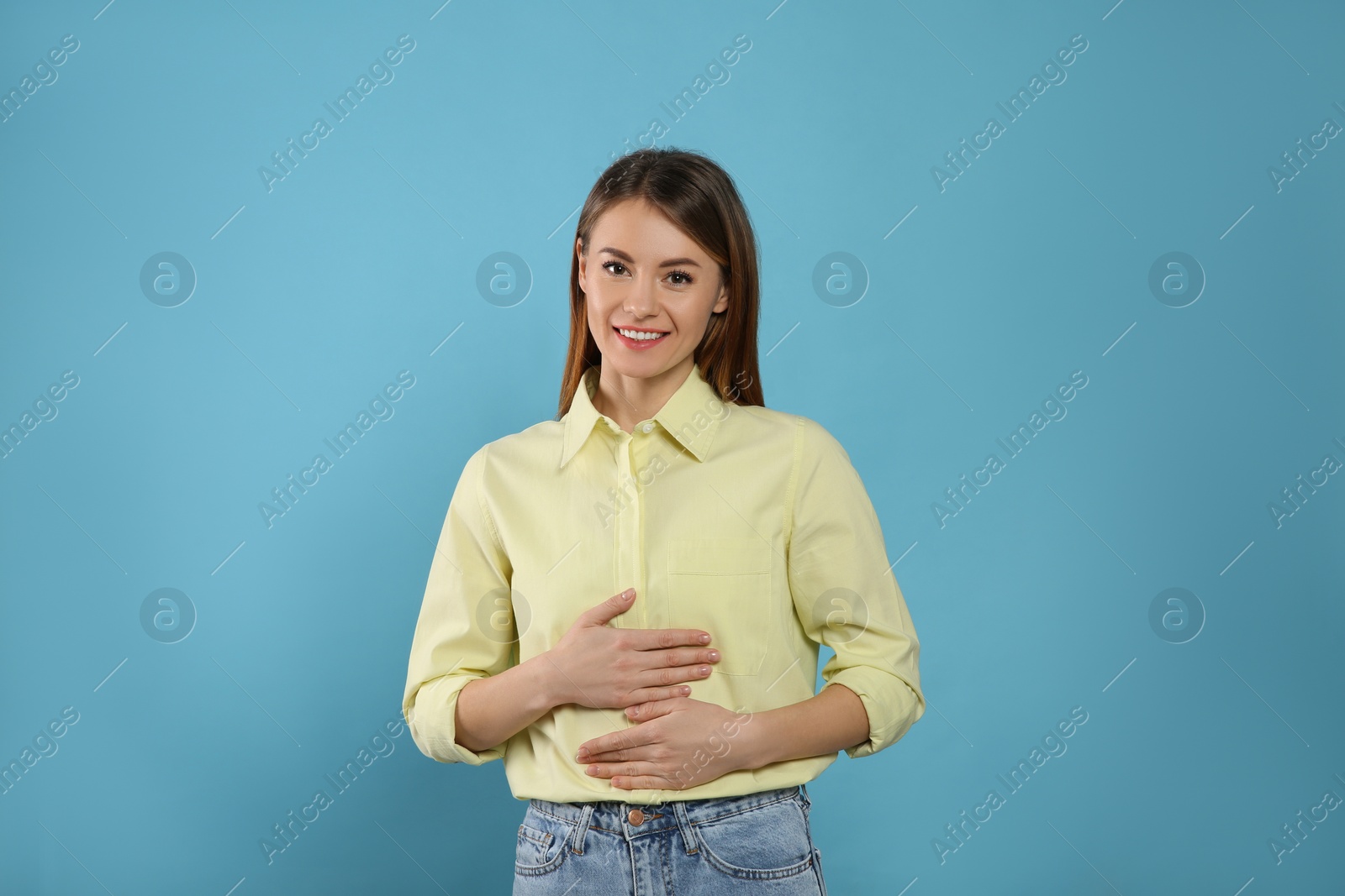 Photo of Healthy woman holding hands on belly against light blue background
