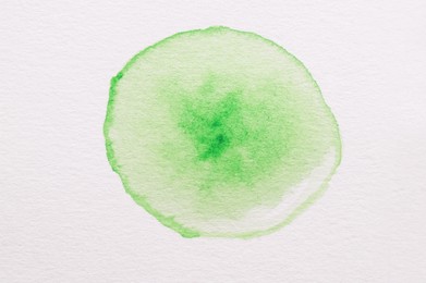 Photo of Green watercolor blot on white canvas, top view