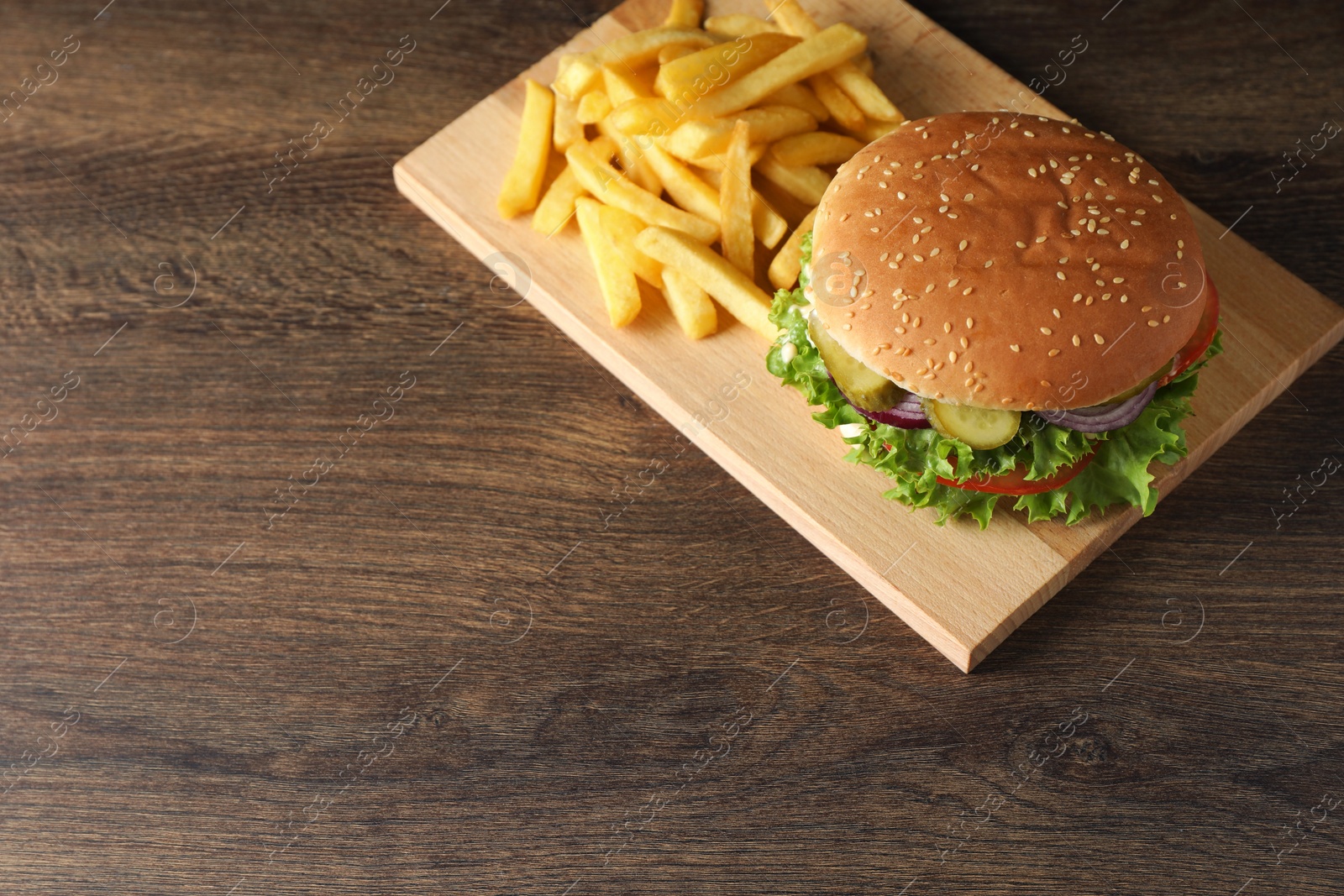 Photo of Delicious burger with beef patty and french fries on wooden table, above view. Space for text
