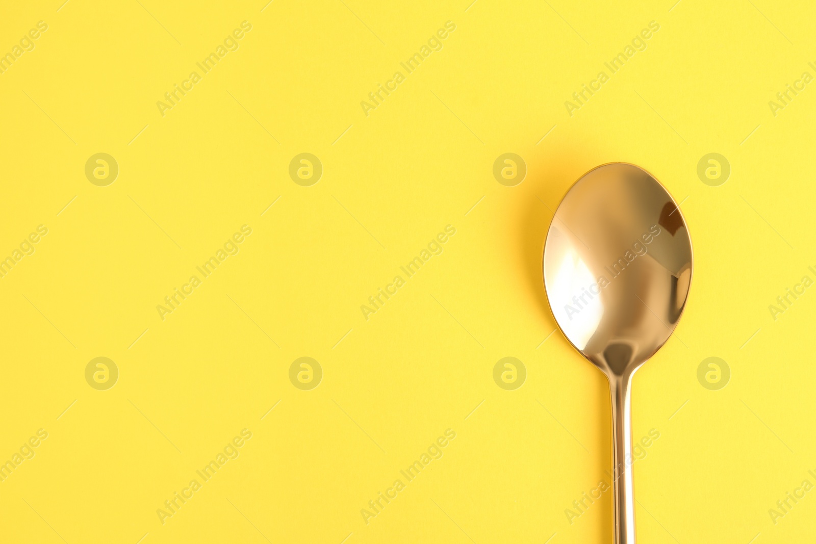 Photo of Clean tea spoon and space for text on color background, top view