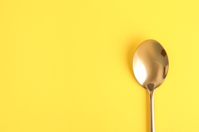 Clean tea spoon and space for text on color background, top view