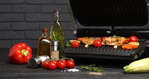 Electric grill with different products on black wooden table