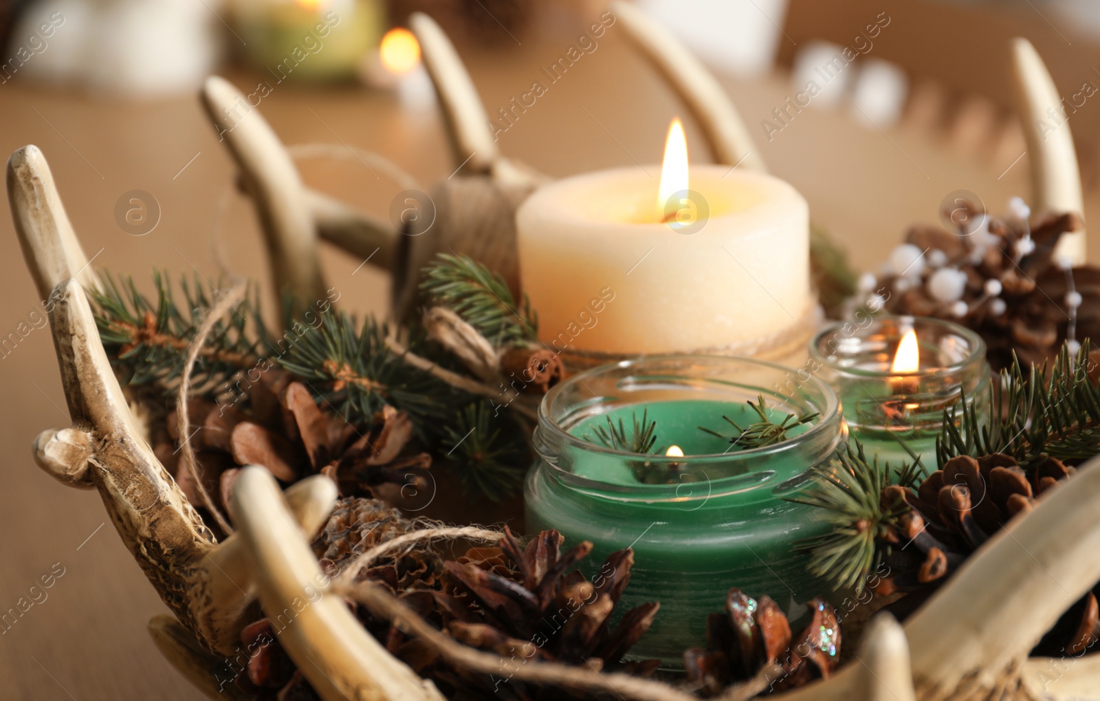 Photo of Burning scented conifer candles with Christmas decor on table, closeup