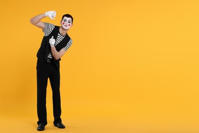 Photo of Funny mime artist posing on orange background. Space for text