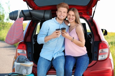 Young couple with luggage near car trunk outdoors