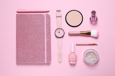 Photo of Flat lay composition with notebook, wristwatch and cosmetics on pink background