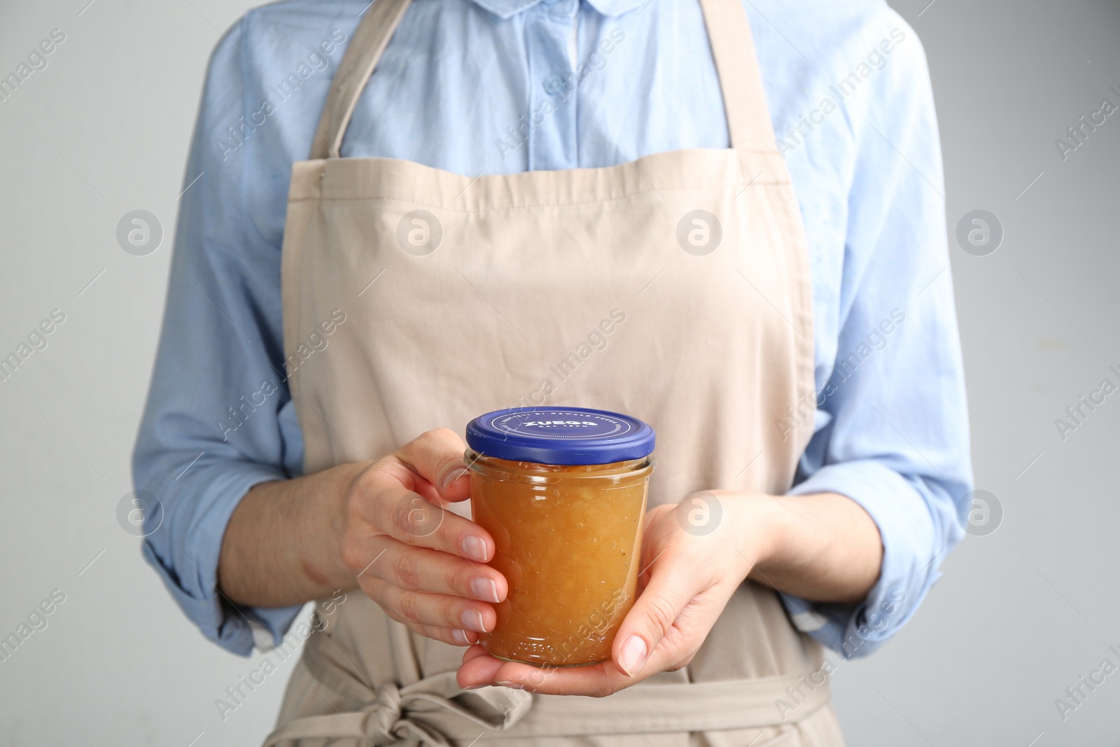 Photo of Woman with jar of delicious pear jam, closeup