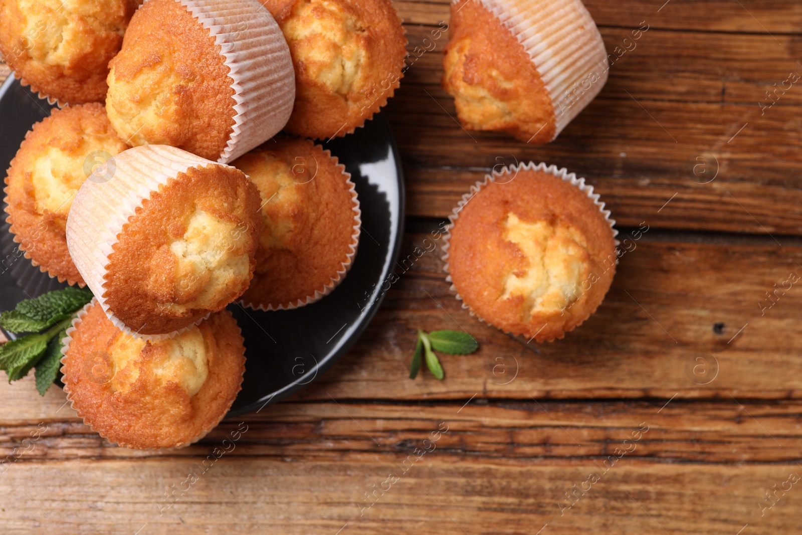 Photo of Delicious sweet muffins on wooden table, flat lay. Space for text