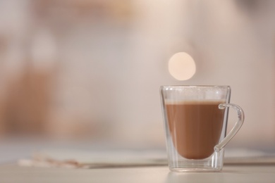 Photo of Cup of aromatic coffee on table against blurred background