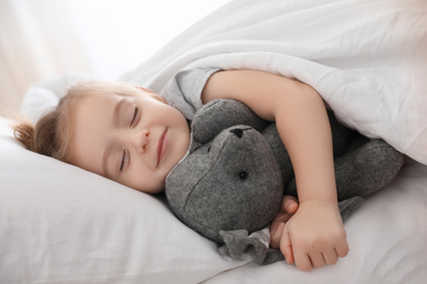 Photo of Cute little girl sleeping with toy bunny at home. Bedtime schedule