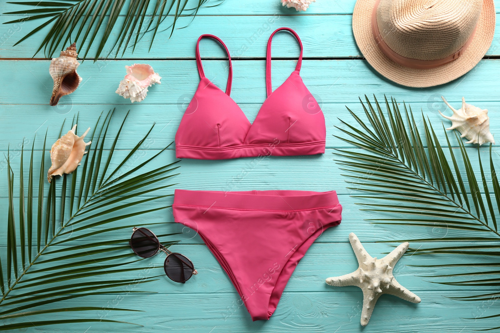 Photo of Beautiful pink bikini and beach accessories on light blue wooden background, flat lay