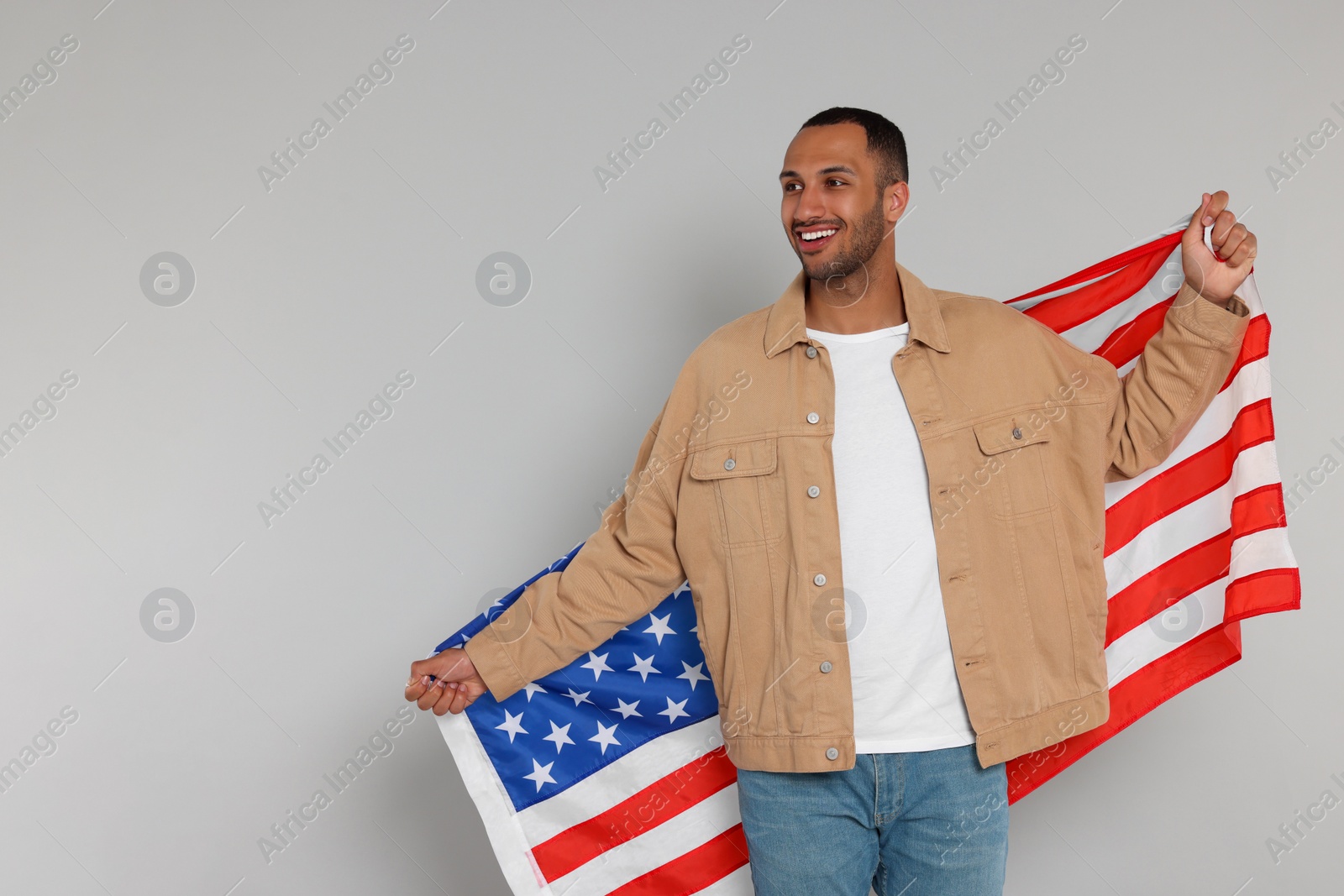 Photo of 4th of July - Independence Day of USA. Happy man with American flag on light grey background, space for text