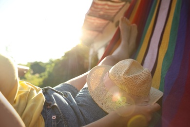 Photo of Young woman with hat resting in hammock near motorhome outdoors on sunny day, closeup