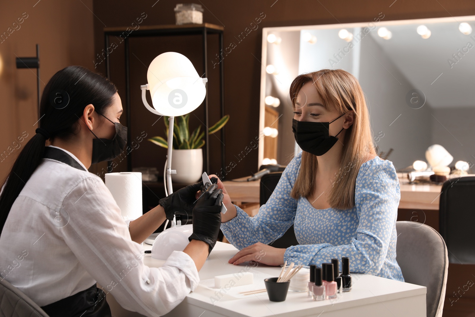 Photo of Professional manicurist working with client in salon. Beauty services during Coronavirus quarantine