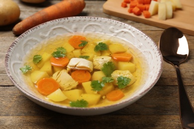 Photo of Dish with fresh homemade chicken soup on wooden table