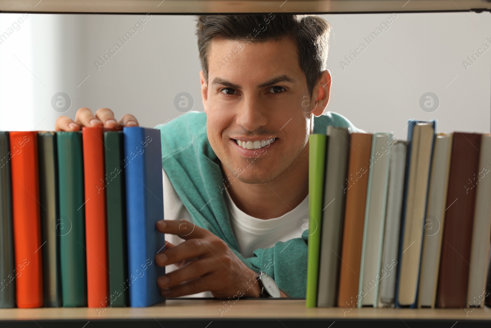 Photo of Man searching for book on shelf in library