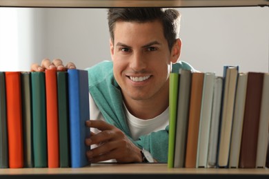 Photo of Man searching for book on shelf in library