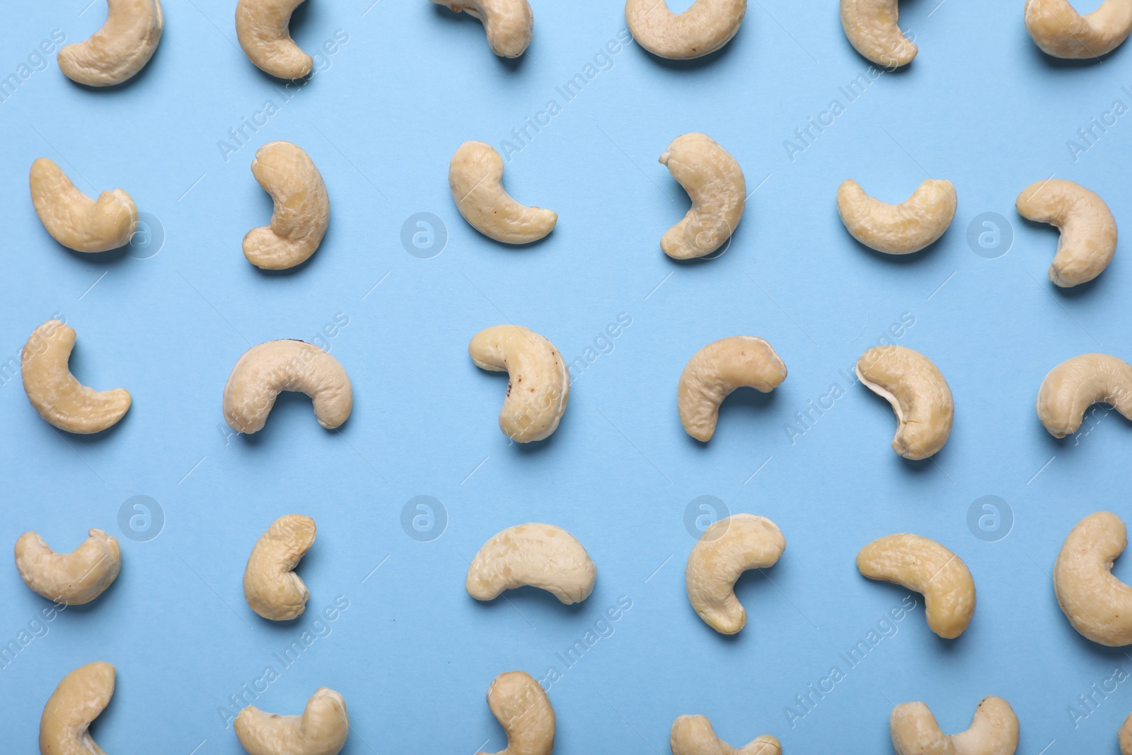 Photo of Many tasty cashew nuts on light blue background, top view