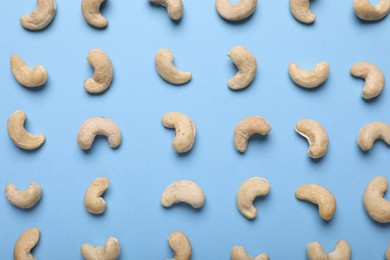 Photo of Many tasty cashew nuts on light blue background, top view