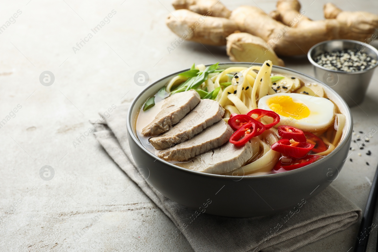 Photo of Delicious ramen in bowl on light textured table, space for text. Noodle soup