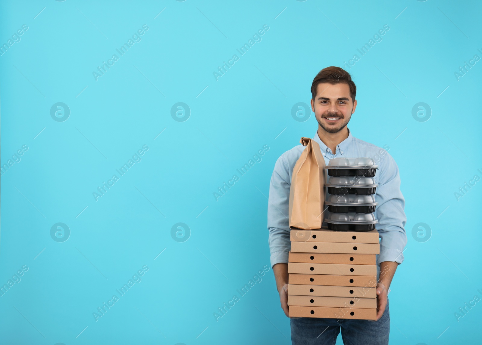 Photo of Young courier with different orders on color background, space for text. Food delivery service