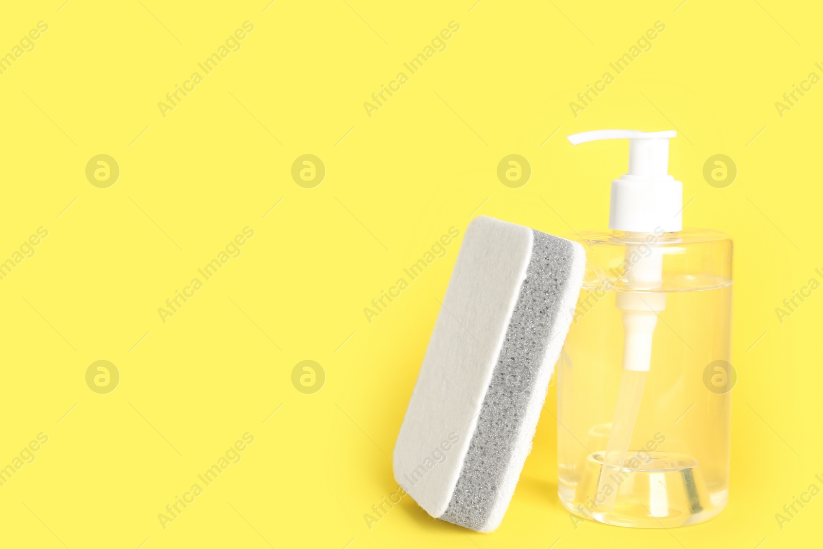 Photo of Detergent and sponge on yellow background, space for text