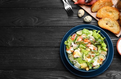 Bowl of delicious cucumber salad served on black wooden table, flat lay. Space for text