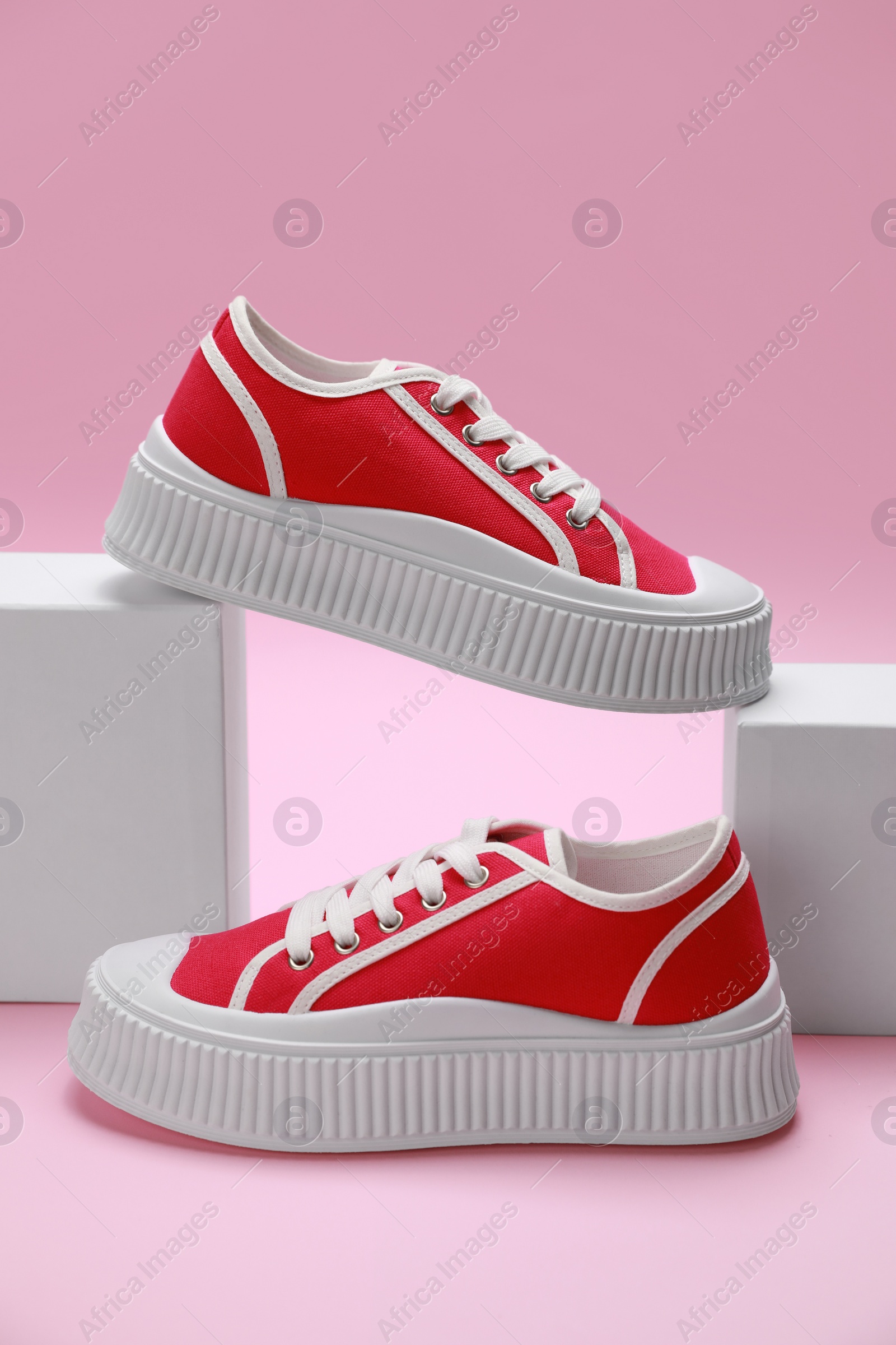 Photo of Stylish presentation of red classic old school sneakers on pink background